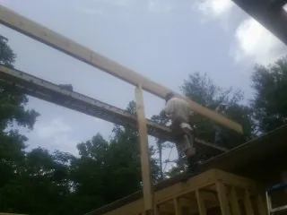 Carpenter setting a ridge beam over a new addition frame — Ice Dam Removal by Roofing Brothers in Hardyville